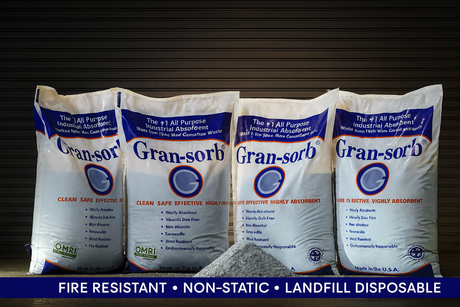 Bags of granular absorbent lined up with a pile of material in front of the bags against a dark background and a text ribbon that reads fire resistant, non-static, landfill disposable.