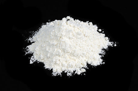 white anti caking powder sitting on a table with black background 