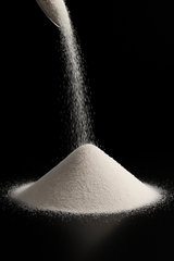 White granular activated alumina being poured onto a pile on a black background