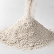 Fine white diatomaceous earth filter aid powder pouring into a mound on a clean neutral background