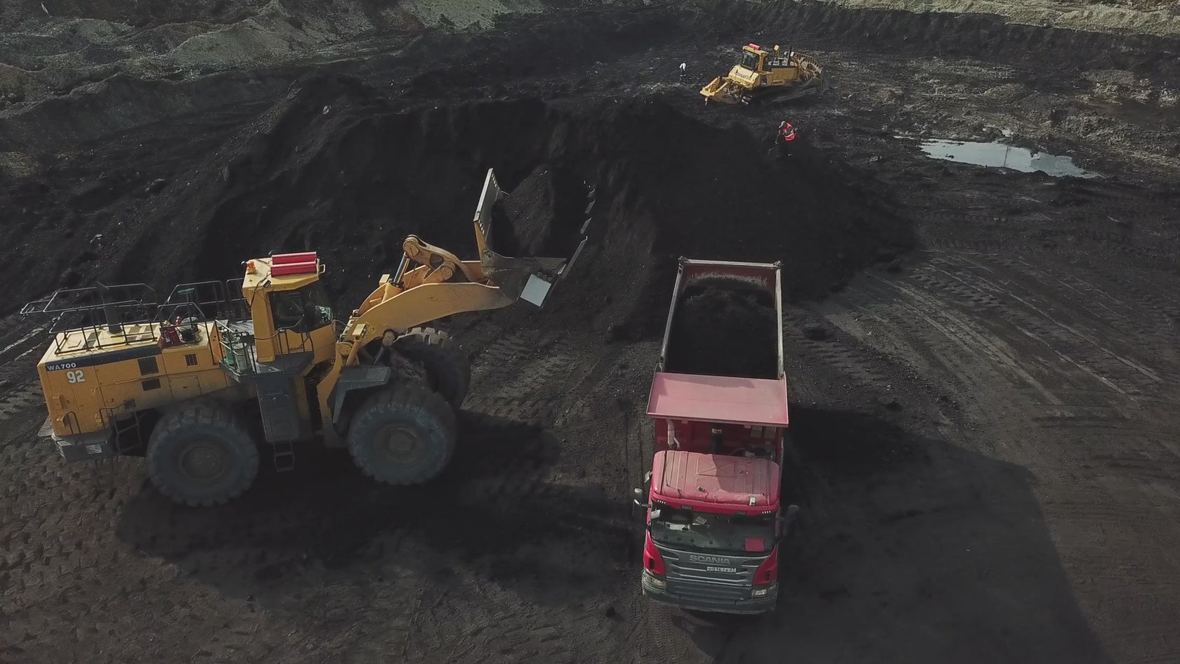 Front loader tractor loading a large dumb truck full of carbon for further processing. 