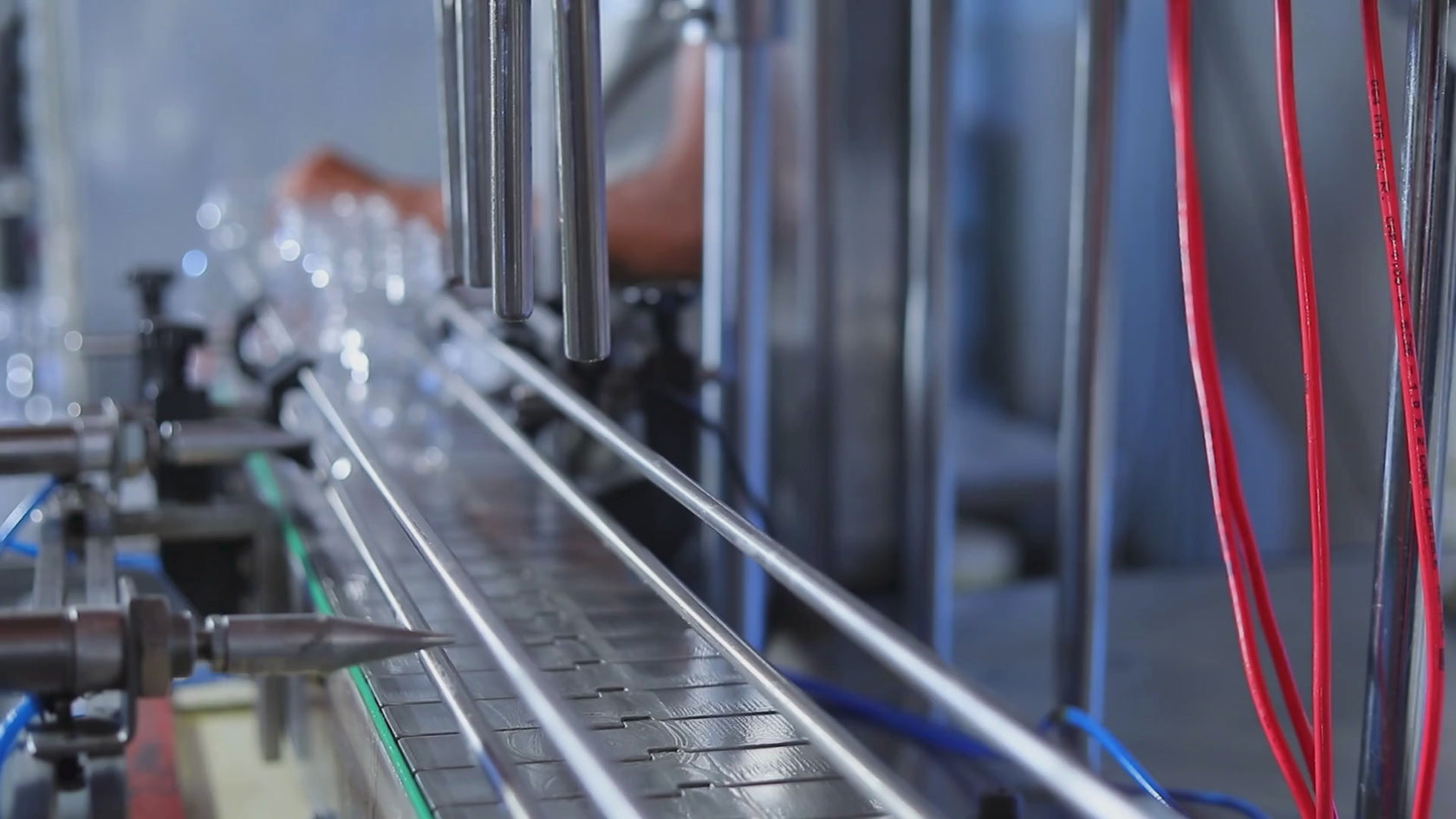 Small glass jars being filled on conveyor belt production line.  
