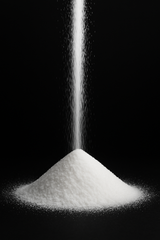 Pile of silica powder being poured against a black background