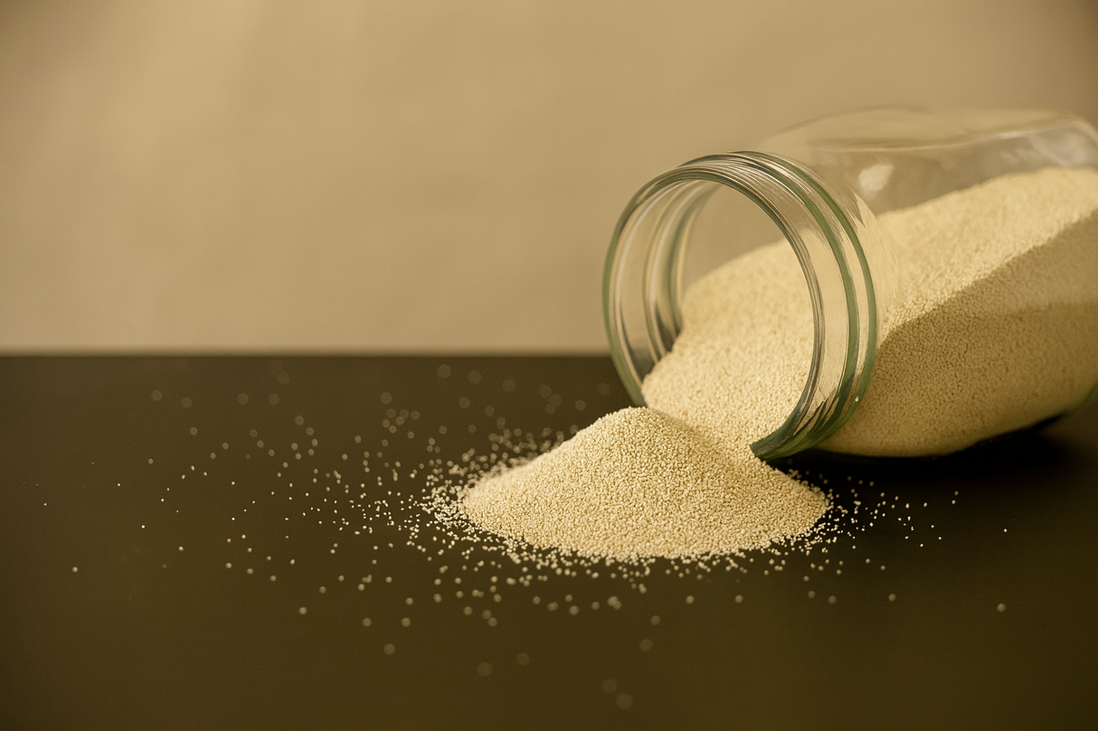 Glass jar of molecular sieve powder spilling onto a dark surface with a beige background