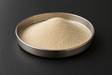 Arkema SILIPORITE NK 10 AP 4A synthetic zeolite molecular sieve powder in a stainless steel sample dish.