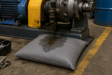Universal absorbent pillow positioned under industrial equipment to capture oil, coolant and water leaks